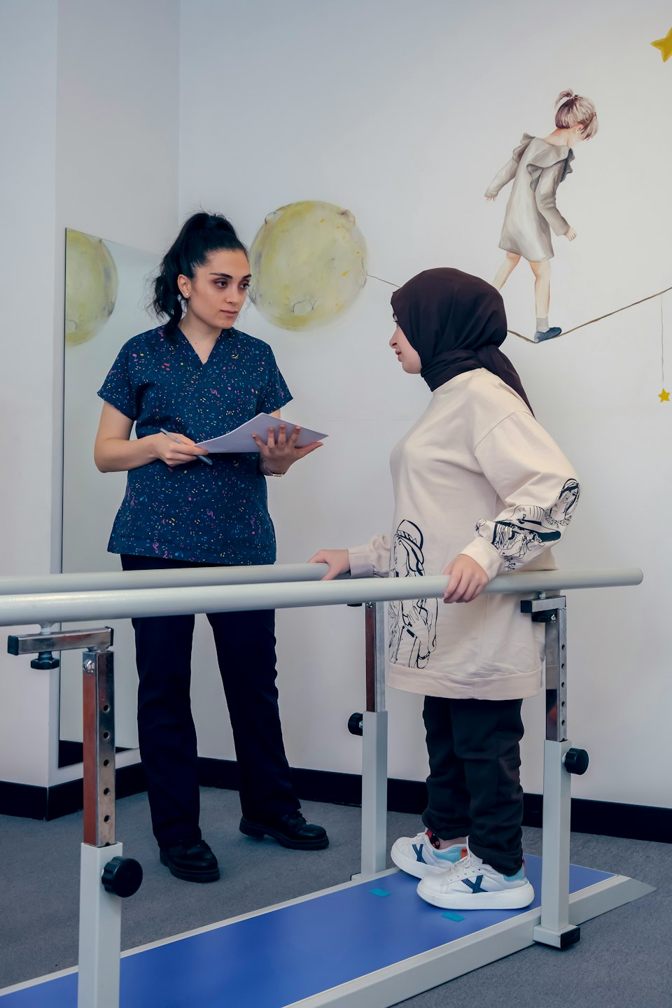 Physical therapist helps patient practice walking with parallel bars.